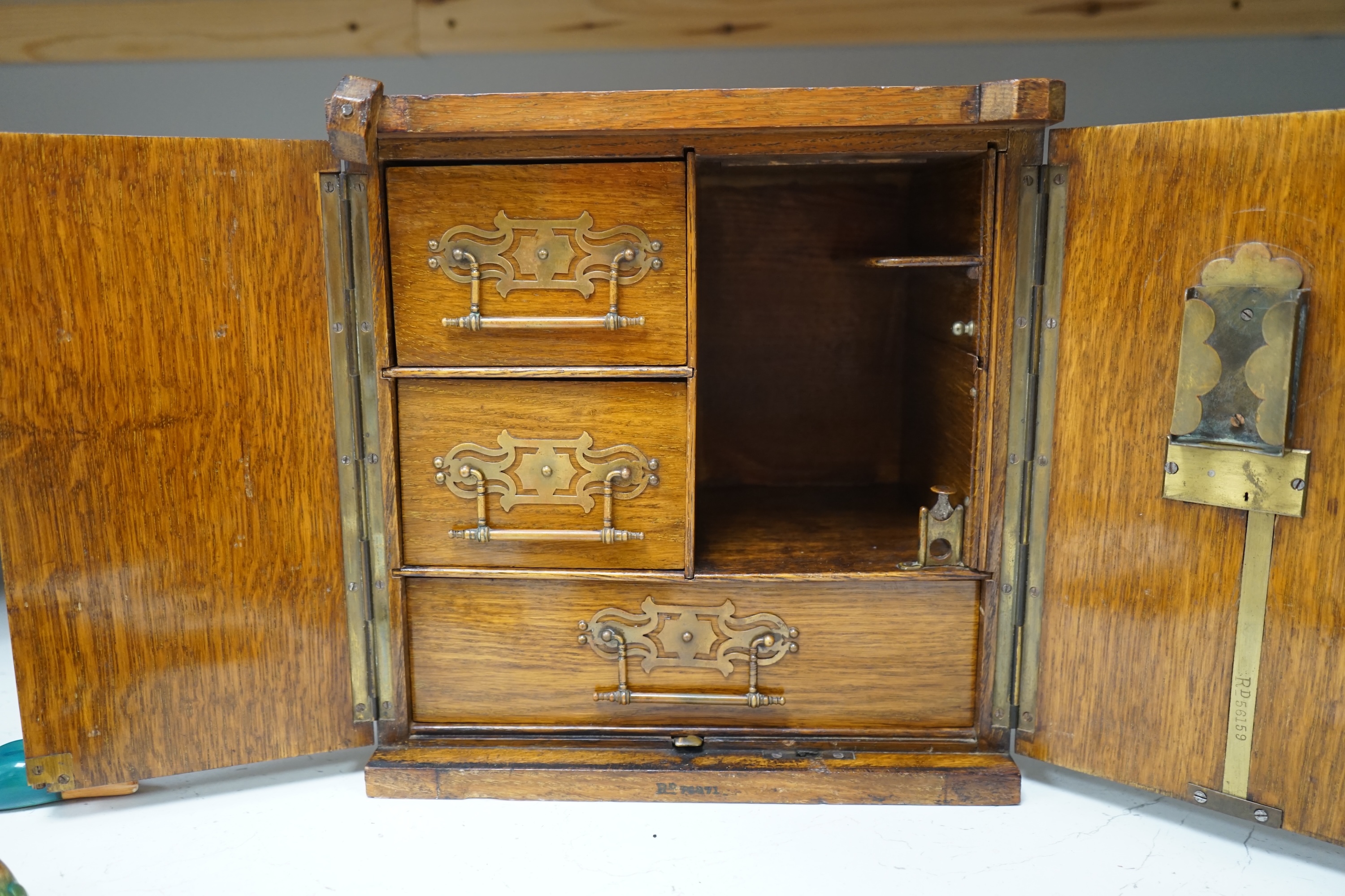 A Victorian oak cigar cabinet modelled as a safe, with brass coat of arms mounts, 30cm wide, 31cm high. Condition - fair